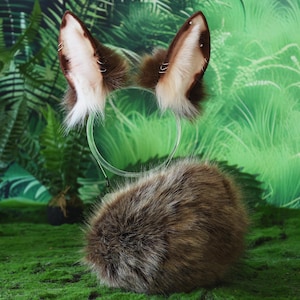May include: A brown and white faux fur headband with matching ears and a fluffy tail. The ears are detailed with small silver hoops. The accessories are designed to resemble a woodland creature.