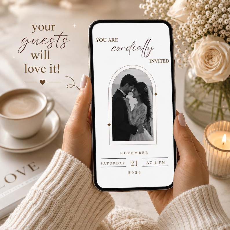 May include: A smartphone displaying a digital wedding invitation with the text YOU ARE cordially INVITED, featuring a black and white photo of a couple inside an arch frame, with the date SATURDAY NOVEMBER 21 2026 AT 4 PM printed below.
