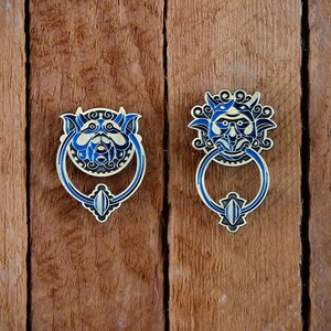 May include: Two ornate door knockers with blue and gold details. The knockers are shaped like faces with intricate designs.
