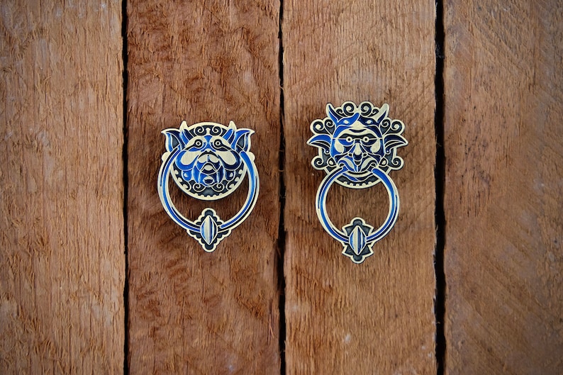 May include: Two ornate door knockers with blue and gold details. The knockers are shaped like faces with intricate designs.