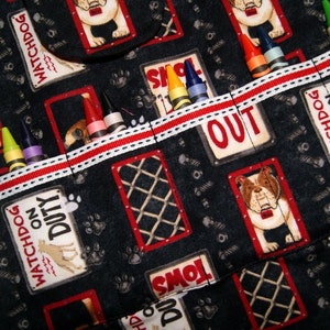 May include: A black fabric organizer with red and white trim. The organizer has multiple pockets with various images of dogs and the text "Watchdog on Duty" and "Keep Out". Crayons are stored in the pockets.