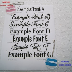 May include: A white sheet of paper with seven different font styles displayed in black. Each font style is labeled with a letter from A to G. The text "SAMPLES GLITTER DESIGN" is at the top of the page. The text "SAMPLES SOLID DESIGN" is at the bottom of the page.