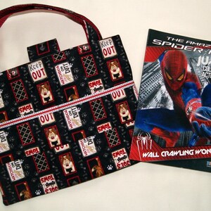 May include: A black and red tote bag with a dog-themed print featuring the text "Watchdog on Duty" and "Keep Out". The bag is next to a coloring book featuring Spiderman with the text "The Amazing Spiderman Jumbo Coloring and Activity Book" and "Wall Crawling Wonder".
