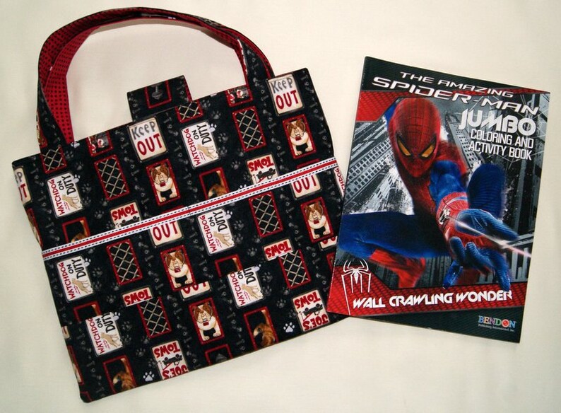 May include: A black and red tote bag with a dog-themed print featuring the text "Watchdog on Duty" and "Keep Out". The bag is next to a coloring book featuring Spiderman with the text "The Amazing Spiderman Jumbo Coloring and Activity Book" and "Wall Crawling Wonder".