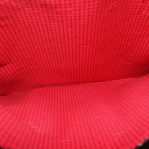 May include: The inside of a red bag with a black polka dot pattern.