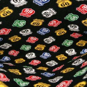 May include: Black fabric with a repeating pattern of colorful Route 66 and Route 99 highway signs. The signs are in various states, including Arizona, California, Illinois, Missouri, and Texas.