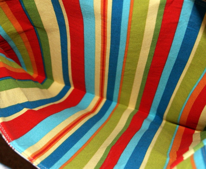 May include: A close-up of the inside of a striped fabric bag. The fabric is a mix of red, blue, yellow, and green stripes.