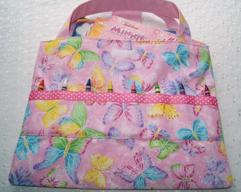 May include: Pink fabric tote bag with a butterfly print and a pocket for crayons. The bag has a pink handle and a white label with the text "Disney Junior Minnie Mouse".