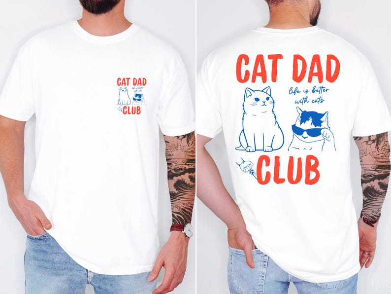 May include: White t-shirt with a red and blue graphic. The front features a small design with two cats and the words "CAT DAD CLUB". The back has a larger design with two cats, the words "CAT DAD", and "life is better with cats".