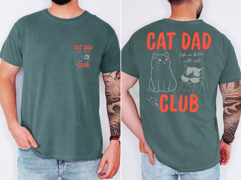 May include: A teal-colored t-shirt with the text "CAT DAD CLUB" in red. The front of the shirt has a small graphic of a cat and the text "CAT DAD CLUB". The back of the shirt has a larger graphic of two cats and the text "Life is better with cats".