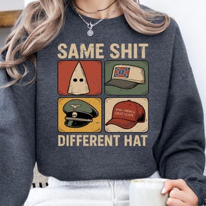 May include: Dark grey sweatshirt featuring the text "SAME SHIT DIFFERENT HAT" and four hat illustrations. These include a white hood, a Confederate flag cap, a military cap, and a red "Make America Great Again" cap.