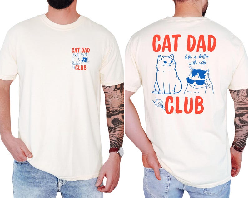 May include: Cream-colored t-shirt with "CAT DAD CLUB" in red text and cat illustrations in blue. The front features a small design, while the back displays a larger graphic with the phrase "life is better with cats."
