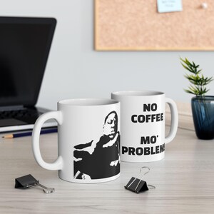 May include: Two white ceramic coffee mugs. One mug features a black and white silhouette of a person. The other mug has the text "NO COFFEE MO' PROBLEM" in black. The mugs are on a light-colored surface.