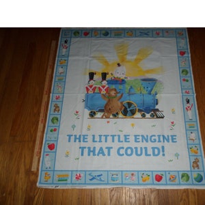 May include: A blue and white fabric panel with a colorful border. The center of the panel features an illustration of a blue train with a bear conductor and the words "The Little Engine That Could!"