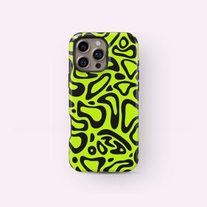 Könnte beinhalten: Eine Smartphone-Hülle mit einem lebendigen, abstrakten Design. Die Hülle hat einen leuchtend neongrünen Hintergrund mit einem sich wiederholenden Muster aus schwarzen, organischen Formen. Die Hülle hat eine glänzende Oberfläche und einen Kameraausschnitt.