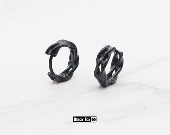 May include: A pair of black hoop earrings featuring a textured, twisted metal design with an irregular, organic surface. The earrings have a hinged closure mechanism and are displayed alongside the text Black Fox with a small fox icon.