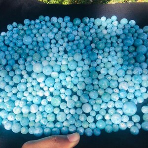 K&ouml;nnte beinhalten: Eine Ansammlung hellblauer, runder Perlen in verschiedenen Gr&ouml;&szlig;en. Die Perlen sind auf einer dunklen Oberfl&auml;che angeordnet und erzeugen einen strukturierten Effekt. Die Perlen scheinen aus einem durchscheinenden Material zu bestehen.