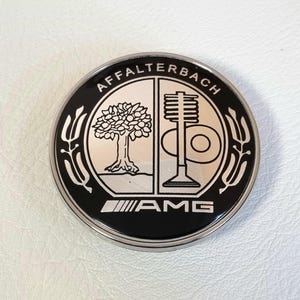 May include: Black and silver round emblem with the text "Affalterbach AMG" and a stylized tree and engine piston design.
