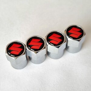 Puede incluir: Juego de cuatro tapones de válvula de vástago de neumático de coche plateados con un logotipo de Suzuki rojo en cada tapón.