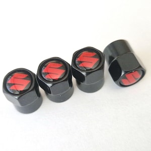Peut inclure: Ensemble de quatre bouchons de valve noirs avec un logo Suzuki rouge. Les bouchons sont hexagonaux et ont une finition brillante, adaptés aux pneus de voiture ou de moto.