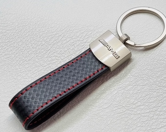 May include: A black leather keychain with red stitching and a silver metal tag that says "AMG".