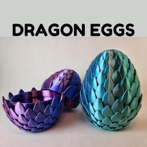 Puede incluir: Tres huevos de dragón decorativos en tonos azules y morados. Los huevos tienen un diseño texturizado en forma de escamas. Un huevo está abierto, revelando un cuenco anidado. El texto "DRAGON EGGS" se muestra encima de los huevos.