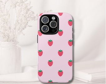May include: A pink phone case with a repeating pattern of red strawberries with green leaves. The case has a black camera module and black side buttons. The phone case is on a white surface.
