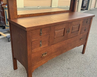 May include: A vintage wooden buffet with a mirror backsplash, featuring multiple drawers and two cabinet doors with decorative carvings. The buffet is made of dark wood with a rich brown finish.