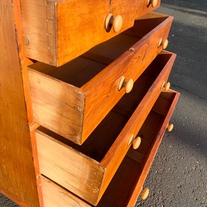 May include: A wooden chest of drawers with four drawers. The drawers are open and the wood grain is visible. The chest of drawers is a light brown color.