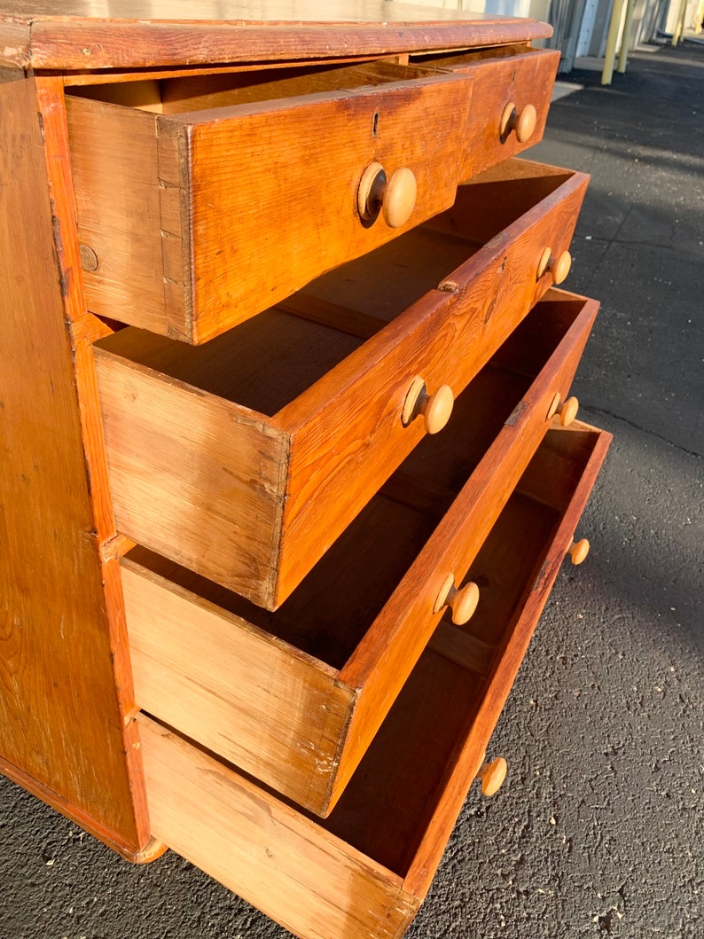 May include: A wooden chest of drawers with four drawers. The drawers are open and the wood grain is visible. The chest of drawers is a light brown color.