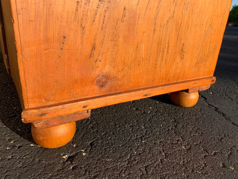 May include: A wooden chest with a natural finish and rounded legs. The chest has a simple design and is made of solid wood.