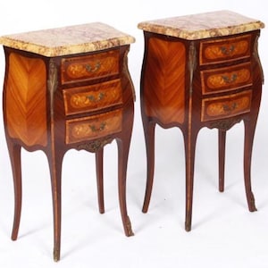 May include: A pair of antique French nightstands with marquetry inlay and marble tops. Each nightstand has three drawers and stands on four cabriole legs.