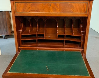May include: A vintage wooden secretary desk with a green felt writing surface. The desk has two drawers and a series of small compartments. The desk is open and the writing surface is visible.