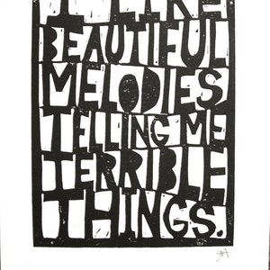 Cita de Tom Waits, tipografía de impresión en bloque de linograbado NEGRO: Me gustan las melodías hermosas que me dicen cosas terribles, 8 x 10, estilo de corte de papel