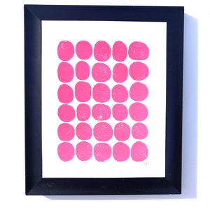 May include: A framed print with a white background and a grid of 36 pink circles.
