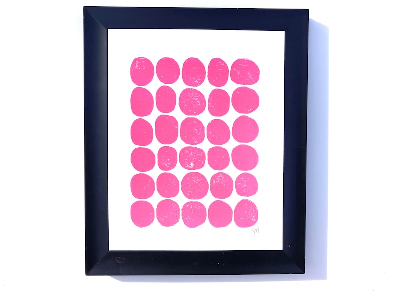 May include: A framed print with a white background and a grid of 36 pink circles.