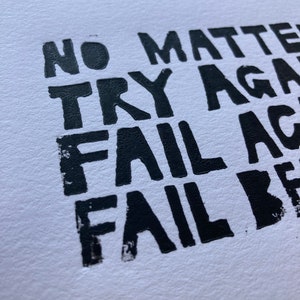 Op de afbeelding: Zwart-witte typografieprint met de tekst "No matter try again fail again fail better".