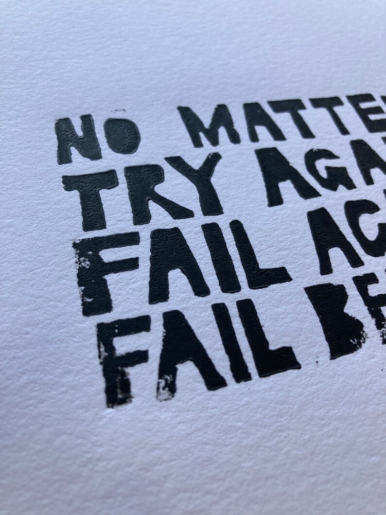 Op de afbeelding: Zwart-witte typografieprint met de tekst "No matter try again fail again fail better".