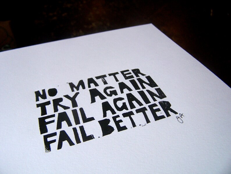 Op de afbeelding: Zwart-wit typografieprint op wit papier met de tekst "No matter try again fail again fail better".