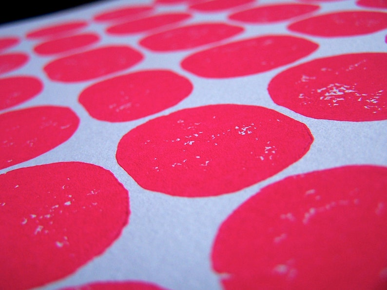 May include: A close-up of a white surface with a repeating pattern of bright pink circles. The circles are slightly textured and appear to be made with paint.