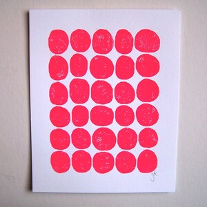 May include: A white card with a grid of 30 pink circles printed on it. The circles are arranged in five rows of six circles each. The card is signed "J&T" in the bottom right corner.