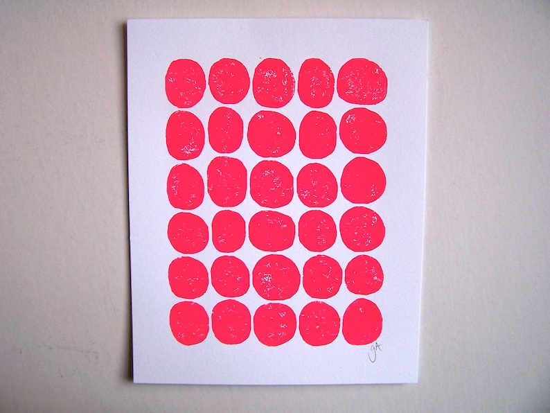 May include: A white card with a grid of 30 pink circles printed on it. The circles are arranged in five rows of six circles each. The card is signed "J&T" in the bottom right corner.