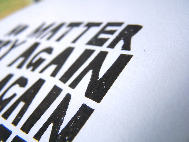 Op de afbeelding: Close-up van een zwart-witte print met de tekst "Het maakt niet uit, probeer het opnieuw".