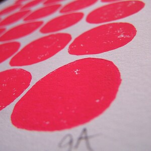 May include: A close-up of a white surface with a pattern of pink circles. The circles are arranged in a staggered pattern, with the larger circles in the center and the smaller circles around the edges.