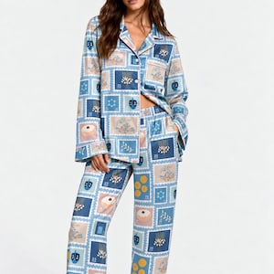 May include: A long-sleeved button-down pyjama shirt and matching elastic-waist pyjama trousers featuring a repeating postage stamp pattern. The print includes illustrations of menorahs, dreidels, doughnuts, and Star of David symbols in blue and tan.
