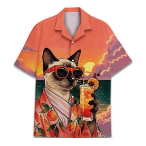 May include: A short-sleeve button-down shirt featuring a graphic print of a Siamese cat wearing red sunglasses. The cat holds a tall glass with an orange slice and straw. The background depicts a sunset over the ocean with orange clouds.