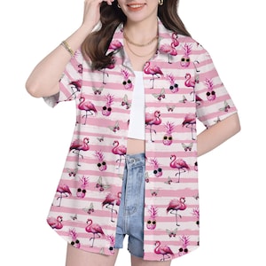 May include: Pink and white striped button-down shirt with a repeating pattern of pink flamingos, pineapples wearing sunglasses, and butterflies. The shirt has short sleeves and a collared neckline. The overall theme is tropical and fun.
