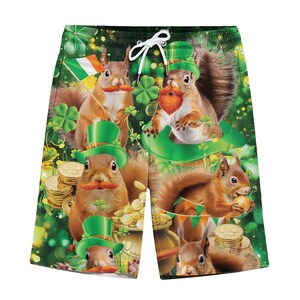 May include: Green and black St. Patrick's Day themed swim trunks featuring multiple squirrels with orange mustaches and green top hats. The squirrels are surrounded by shamrocks, gold coins, and Irish flags. The shorts have a white drawstring.