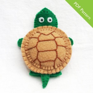 May include: A felt turtle toy with a green shell and brown spots. The turtle has large white eyes and a small mouth. The toy is perfect for children to play with.