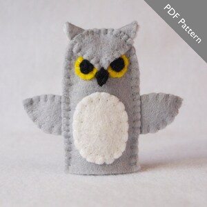 May include: A gray felt finger puppet owl with yellow eyes and a white belly. The owl has stitched details and is a PDF pattern.